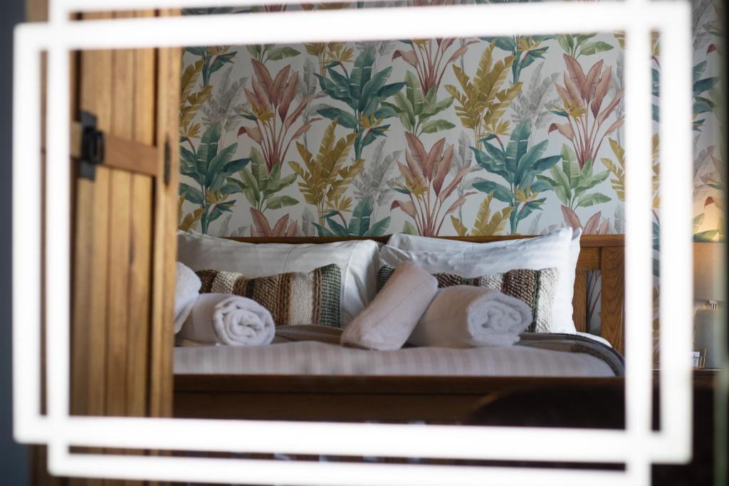 BinghamThe Wheatsheaf Pub, Kitchen & Rooms的一张带白色枕头和花卉壁纸的床