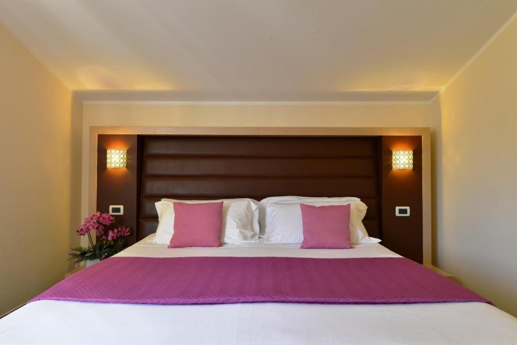 罗西尼亚诺－索尔瓦伊Hotel Rosignano的卧室配有带粉色和白色枕头的大床