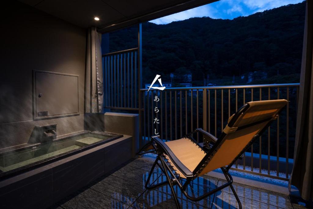 水上町Minakami Onsen Aratashi Minakami的椅子坐在一个配有浴缸的阳台