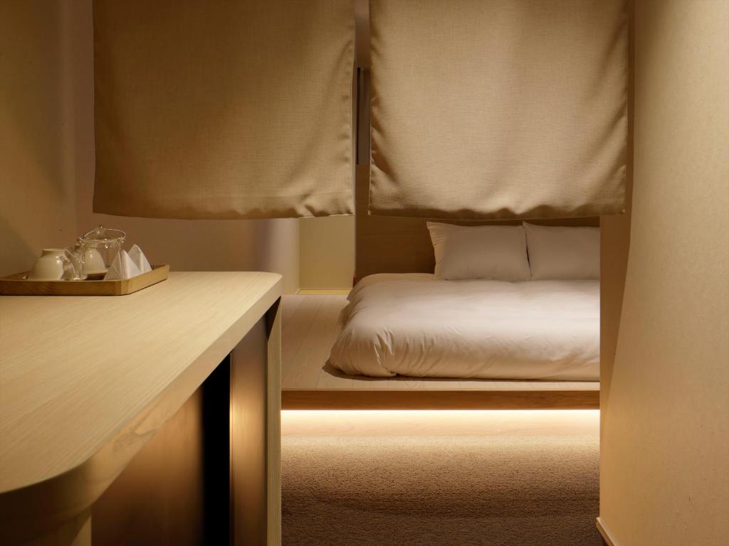 金泽SOKI Kanazawa的一间卧室配有一张床和一张书桌,配有一张四柱床