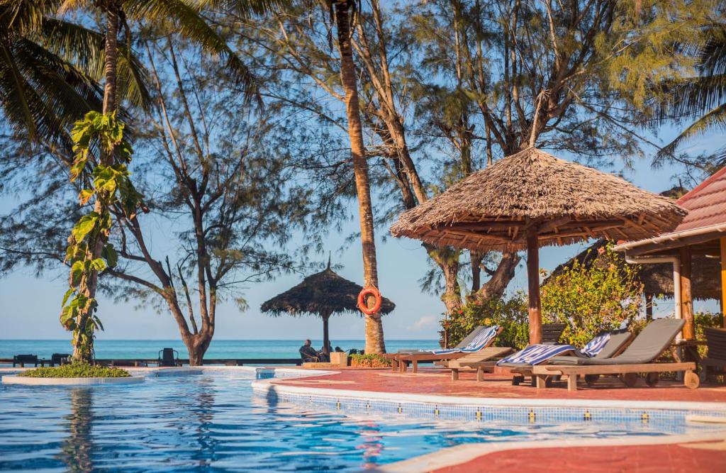 南威Mnarani Beach Cottages的度假村的游泳池,配有椅子和遮阳伞