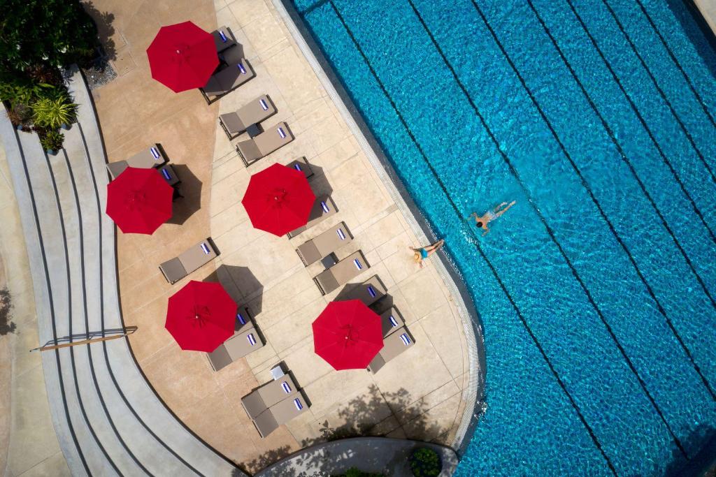 芭堤雅市中心芭堤雅阿玛瑞度假酒店的享有带红伞的游泳池的顶部景致