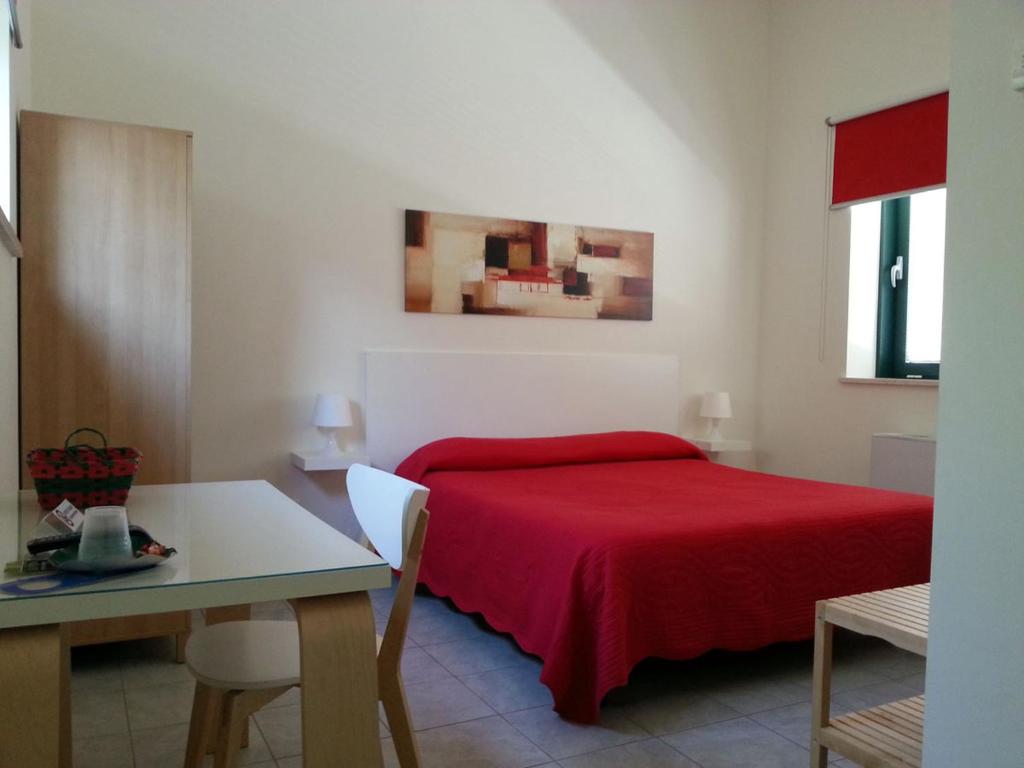 特拉莫竹屋旅馆及公寓的一间卧室配有红色的床和一张桌子