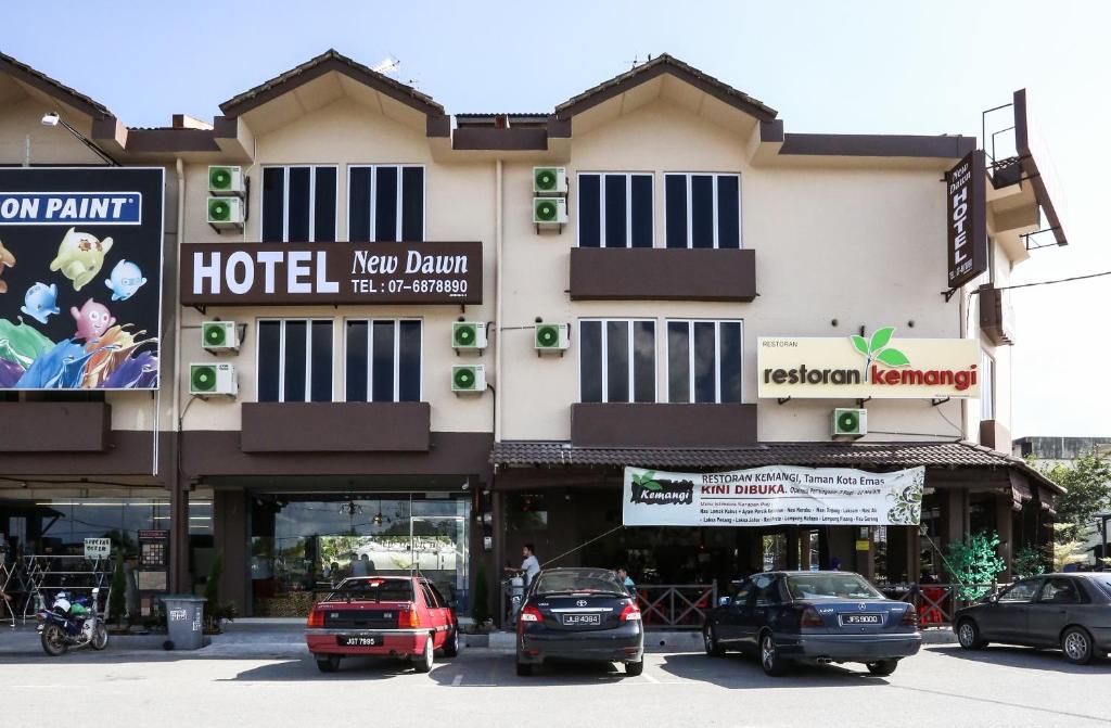 小笨珍New Dawn Hotel Pontian Sdn Bhd的门前有车辆停放的酒店