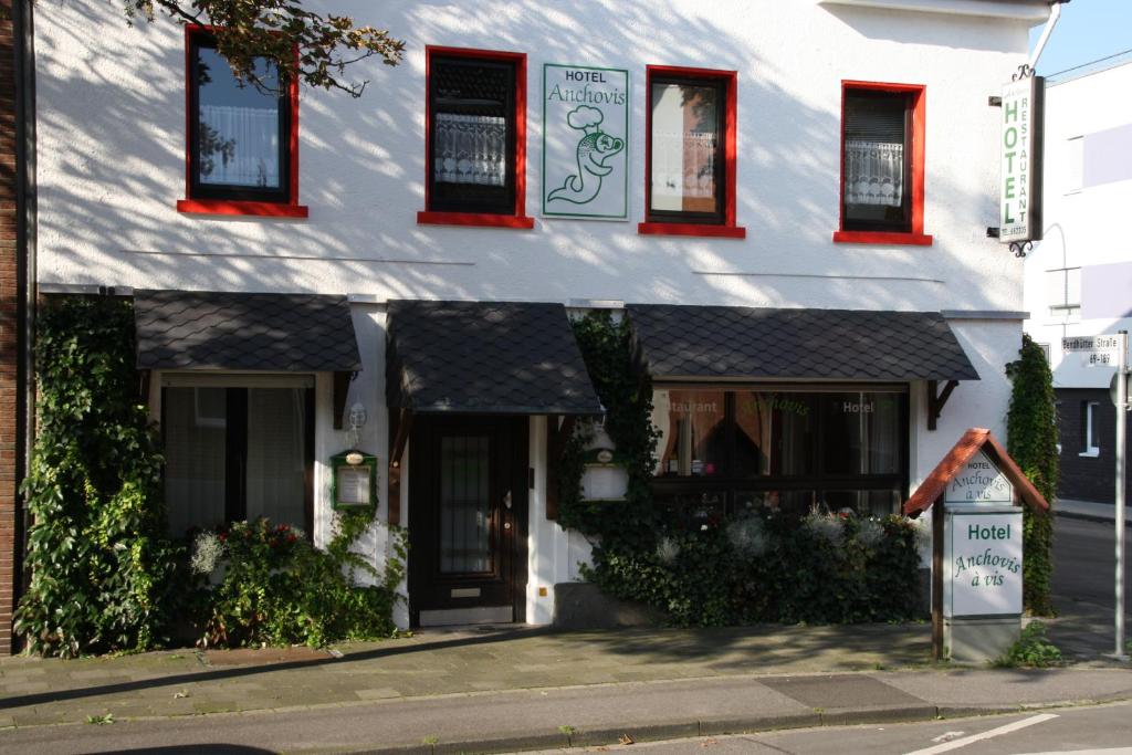 门兴格拉德巴赫Hotel Anchovis的白色的建筑,在街上有红色的窗户