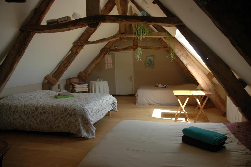 Saint-Hilaire-PetitvilleChambre d'Hôte La Maison du Mesnil的阁楼卧室配有两张床和一张桌子