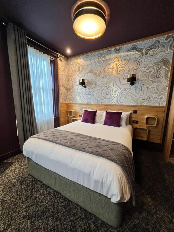 斯特兰福德Lough Rooms at The Artisan的酒店客房配有一张带紫色枕头的大床