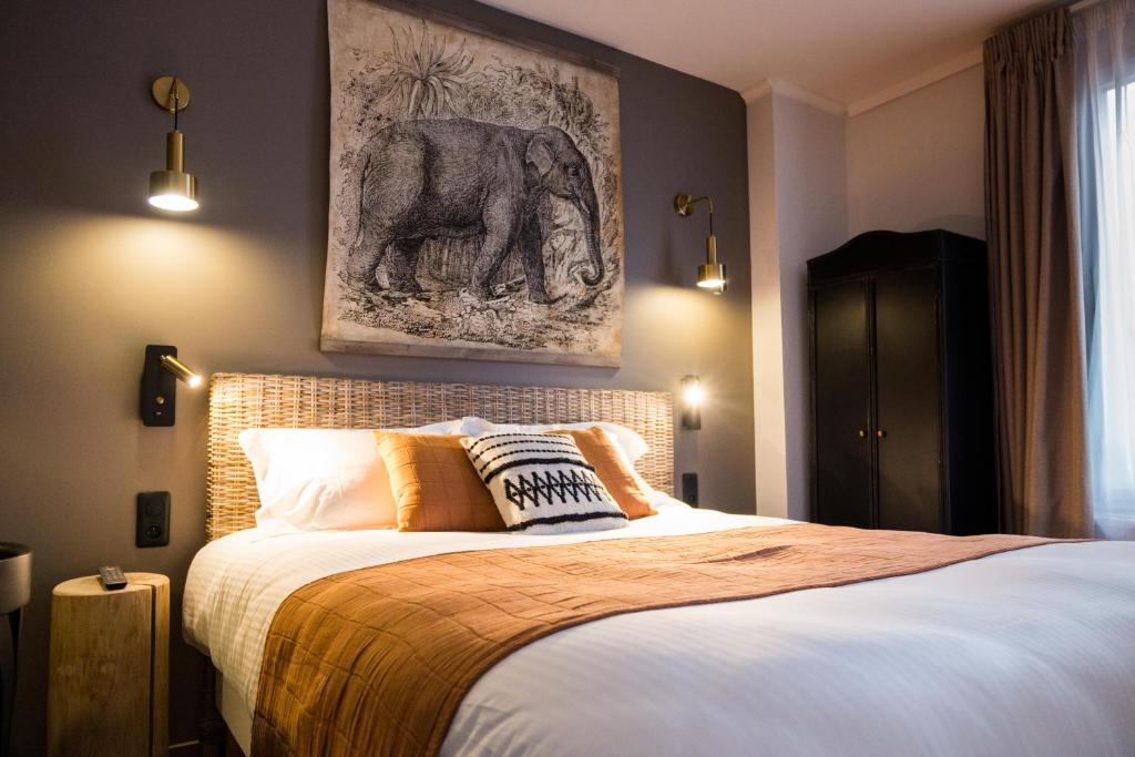 多维尔Hotel Le Patio - Deauville的卧室配有一张挂着大象照片的床。