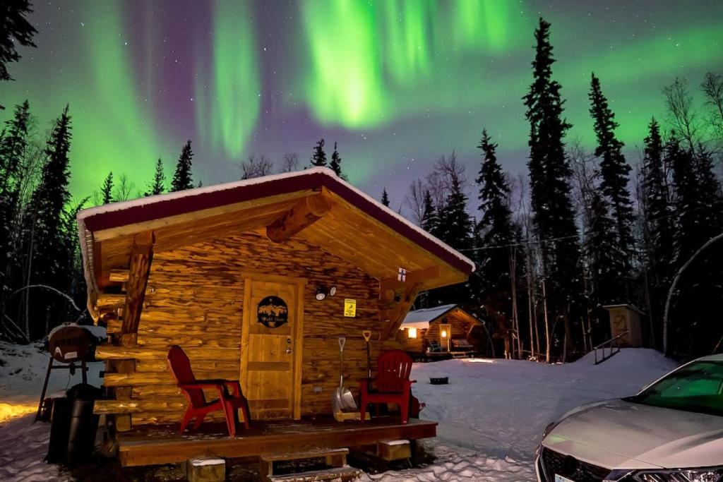 费尔班克斯1 Bd Deluxe Log Cabin View Northern Lights的小屋配有椅子,天空中充满极光