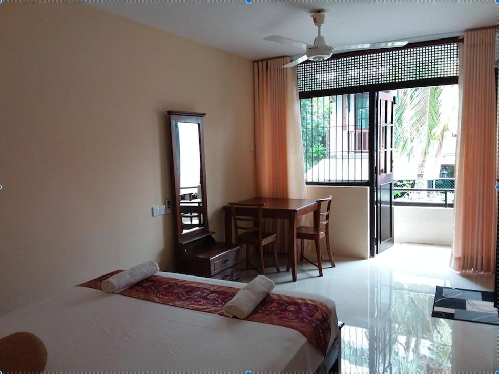 科伦坡科伦坡度假屋的一间卧室配有一张床铺和一张桌子,并设有一个阳台