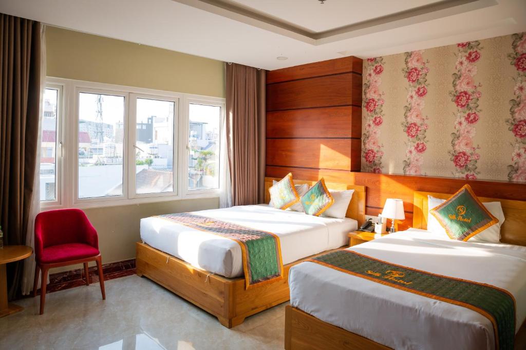 胡志明市Silk Hotel near Tan Son Nhat Airport的酒店客房,设有两张床和一张红色椅子
