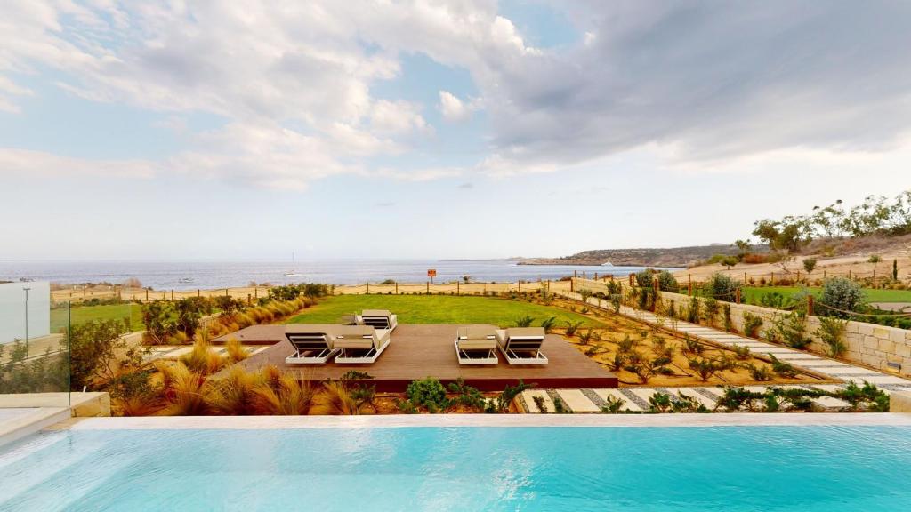 普罗塔拉斯Periyiali Konnos Villas Beach Resort的一个带椅子的游泳池,享有海景