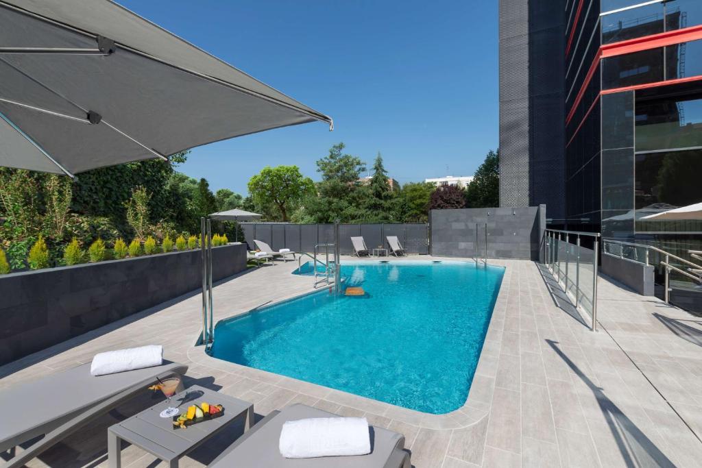 马德里NH马德里里贝拉格兰德曼萨纳雷斯酒店的一座大楼顶部的游泳池