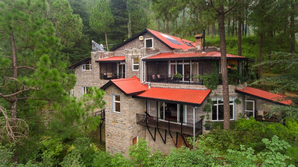 西姆拉SaffronStays Ekam, Chail - forest villa near Chail cricket ground的森林中一座带红色屋顶的大房子