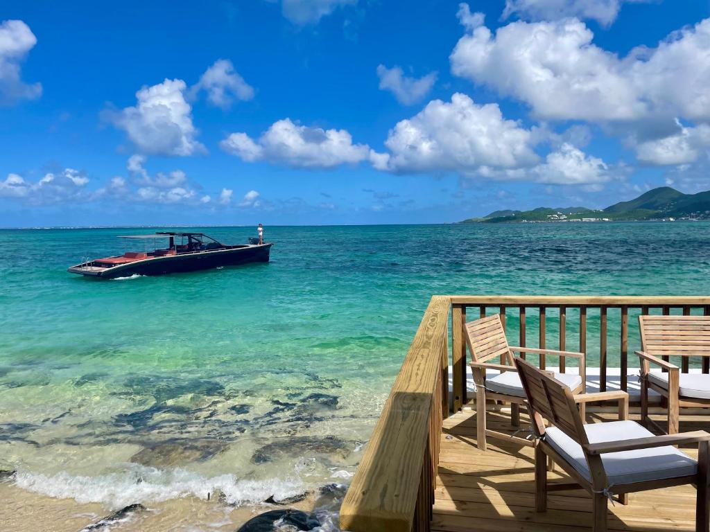 Baie NettleLa Plage Bleue feet in the water with swimming pool的码头椅子旁边的水中小船