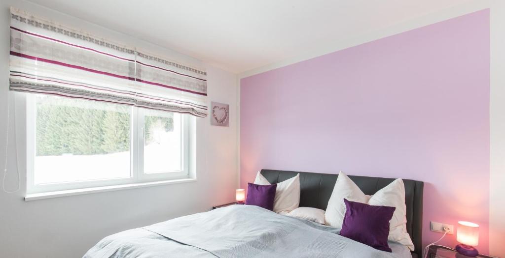 恩斯塔尔豪斯克里斯特公寓的一间卧室配有一张带紫色枕头的床和窗户。