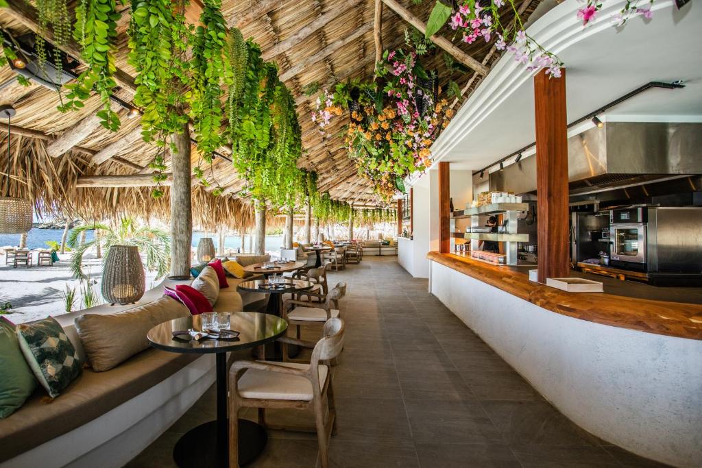 Blue BayVrijstaande BB BEACH Villa Azure的一间设有桌椅的餐厅,种植了植物
