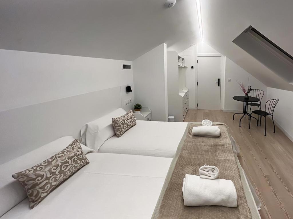 庞特维德拉Hostel Charino的白色的客房设有一张大床和一张桌子。