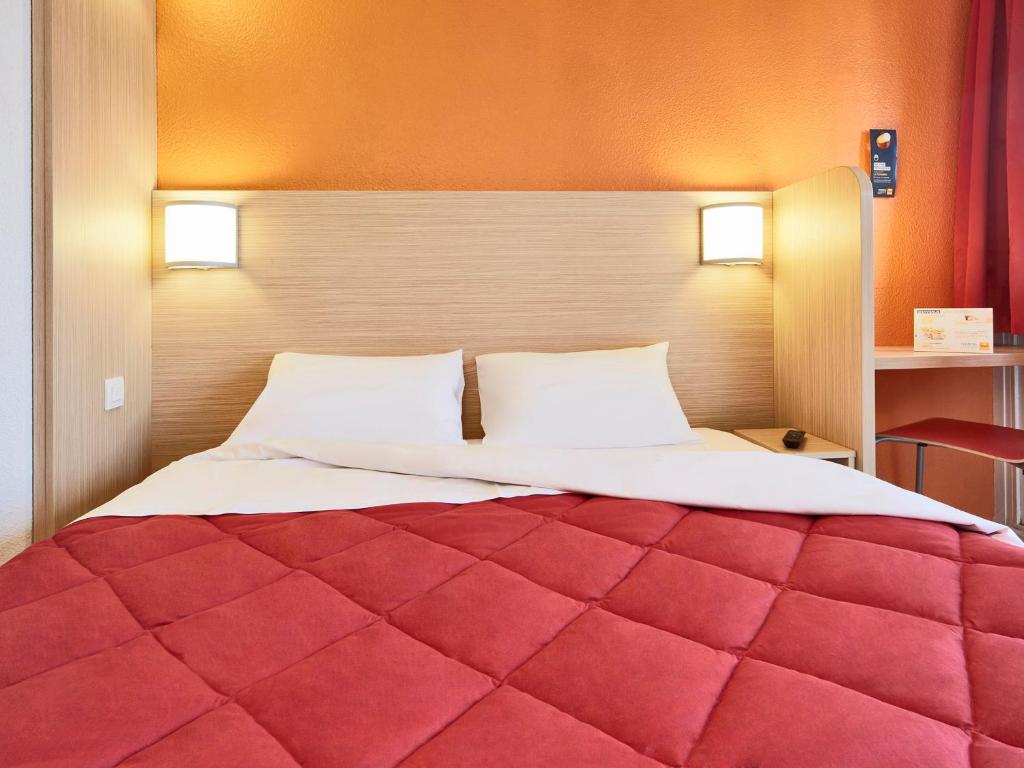 拉沙佩勒圣梅曼西奥尔良 - 圣梅曼礼拜堂普瑞米尔经典酒店的一间卧室配有一张红色大床和两个枕头