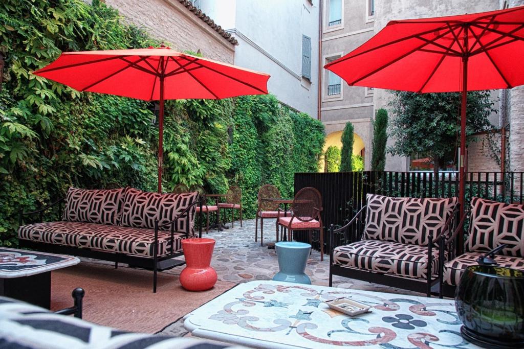 帕尔马Bellacorte Gentiluogo per Viaggiatori的一个带两张沙发和一把红色遮阳伞的庭院