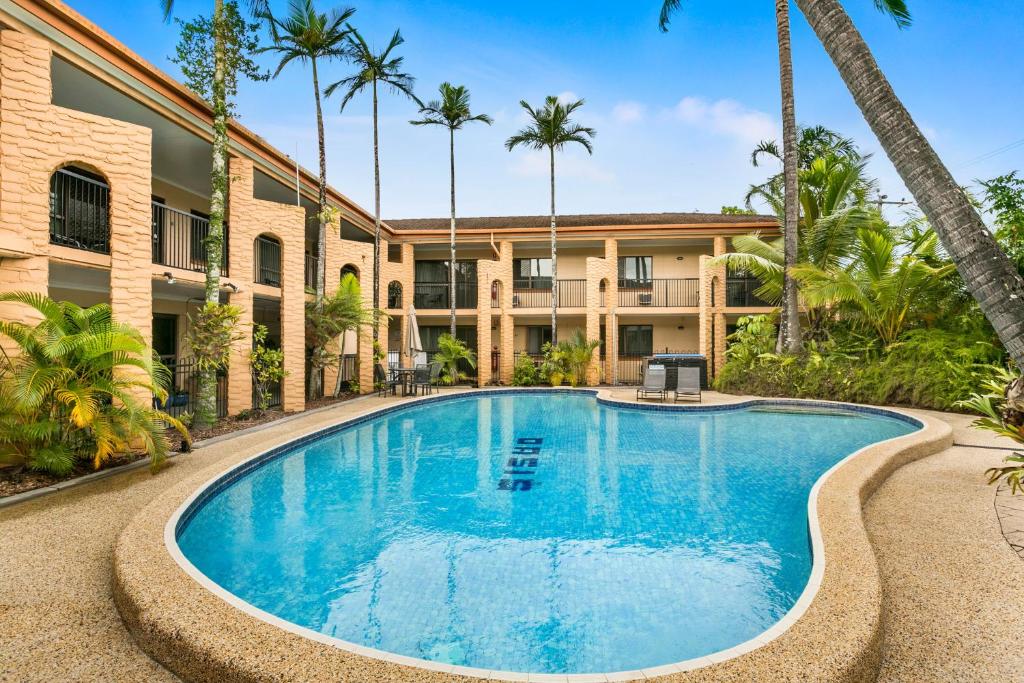 凯恩斯绿洲公寓式酒店的棕榈树建筑前的游泳池