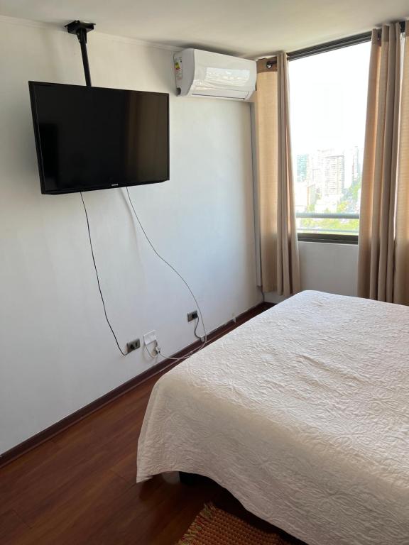 圣地亚哥Acogedor Depto excelente vista, A/C的卧室配有一张床和壁挂式平面电视。
