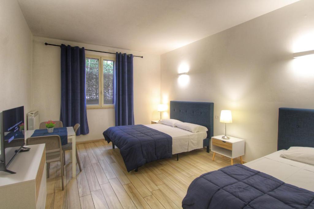 罗马Dalmati House San Lorenzo的一间卧室配有两张床、一张桌子和一台电视。