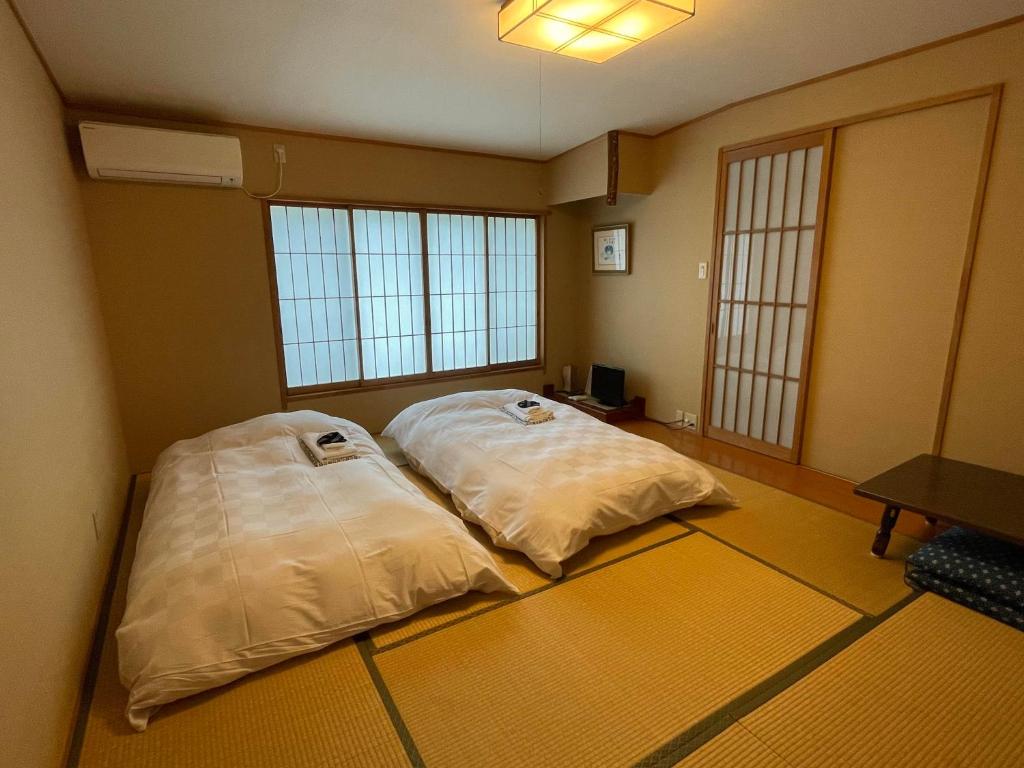 东京福田酒店的带2扇大窗户的客房内的2张床