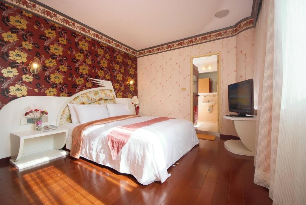丰原区乔苑饭店的卧室配有白色的床和电视。