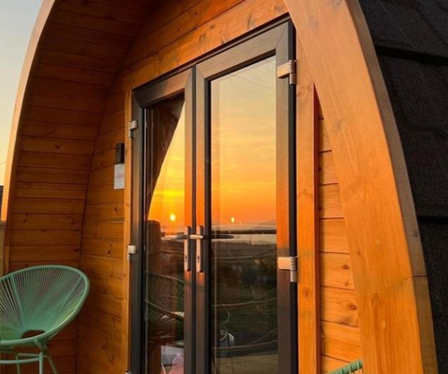 阿契提布The Sleepy Crofter Glamping - Achiltibuie的客房设有可欣赏日落美景的窗户。
