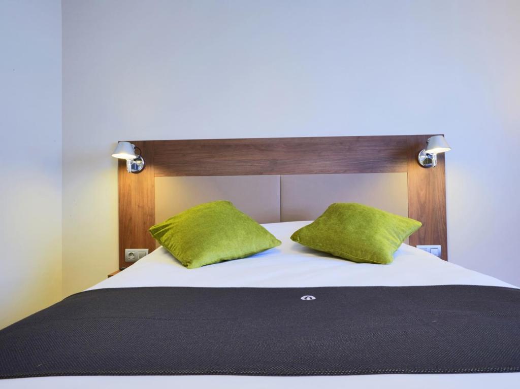 梅里尼亚克波尔多西部 - 梅里尼亚克机场钟楼酒店的一间卧室配有一张带绿色枕头的床
