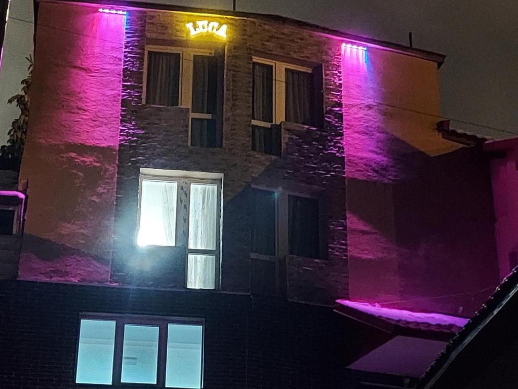 斯特拉扎Pensiunea LUCA Straja的建筑的侧面有粉红色的灯
