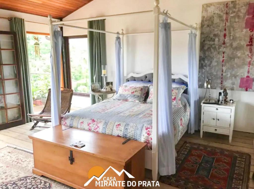 彼得罗波利斯Casa Mirante do Prata no Vale das Videiras的一间卧室配有一张天蓬床和一张桌子