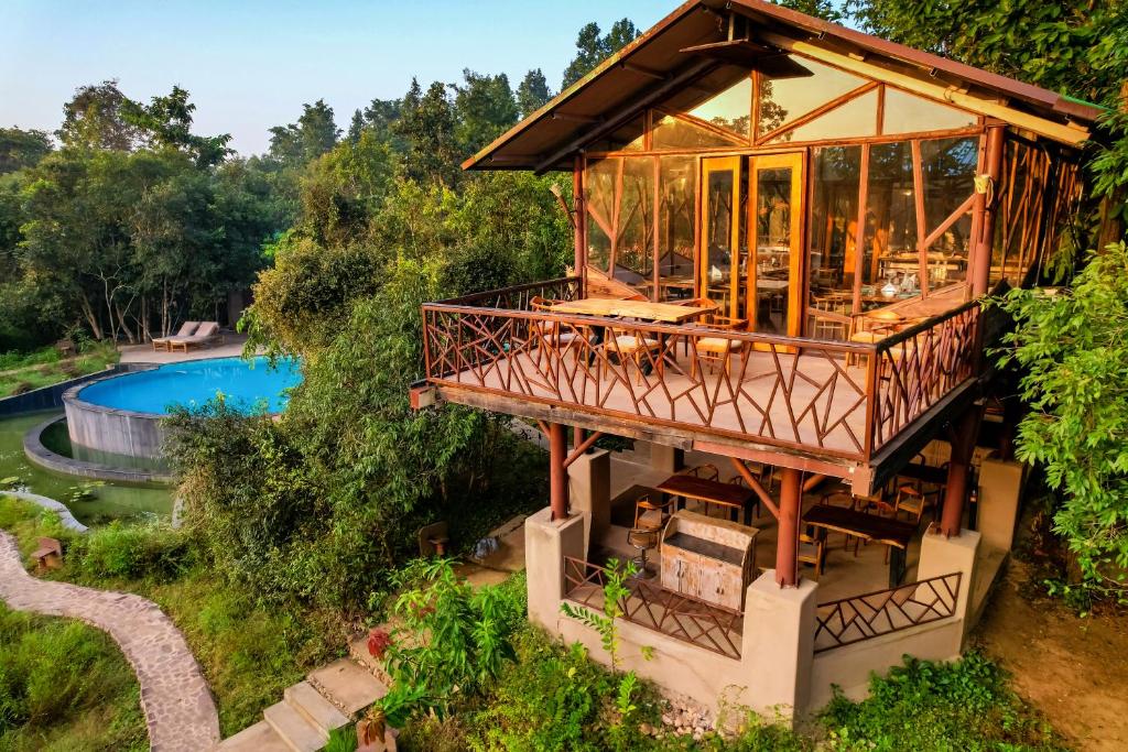 坎哈Kanha Jungle Camp的一座带环绕甲板和游泳池的房子