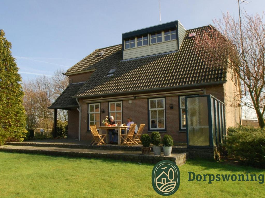 伦德Authentic Holiday Home in North Brabant by the Forest的一对夫妇坐在房子前面的桌子上