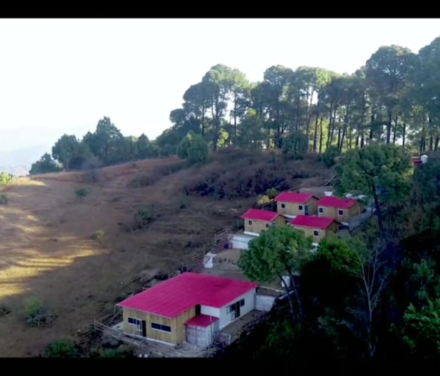 KandāghātSecret Staycation Nature Cottages的山丘上一群有红色屋顶的房屋