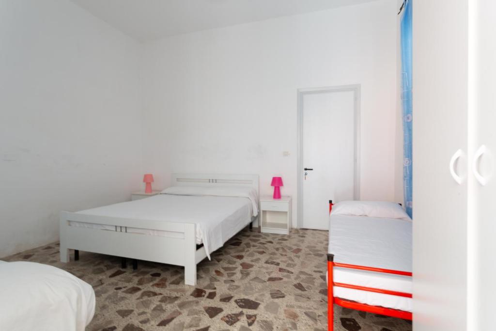 托雷莫泽Appartamento fronte mare e spiaggia的一间白色卧室,配有两张床和粉红色花瓶