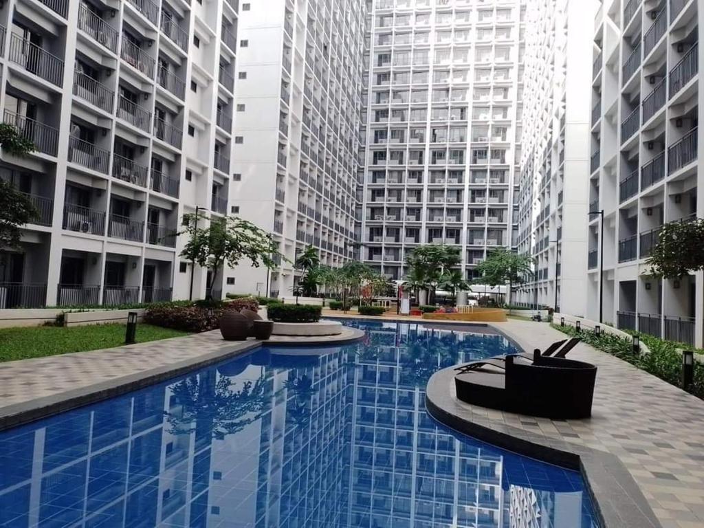 马尼拉Your home in the city的两个高楼中间的一个大型游泳池