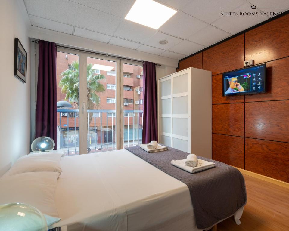 瓦伦西亚Suites Rooms Valencia的一间卧室设有一张床、电视和窗户