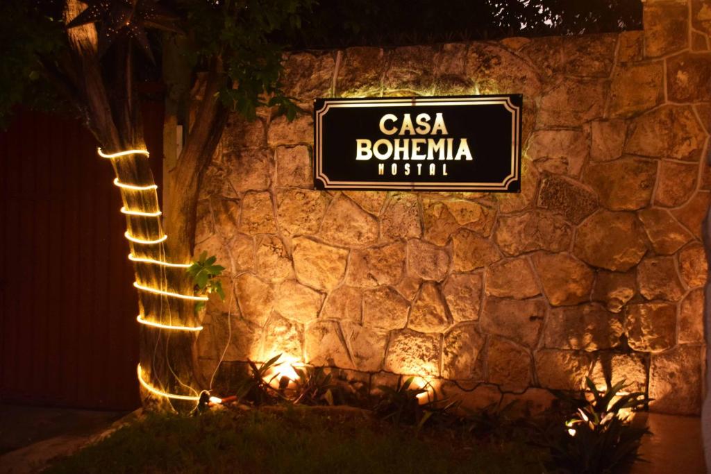 梅里达Hostal Casa Bohemia的石墙上灯亮着的卡萨波南扎的标志