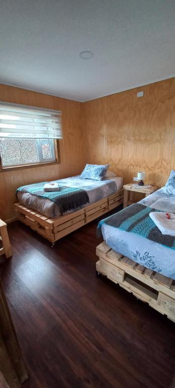 纳塔列斯港Cabañas Sierra Dorotea的铺有木地板的客房内的两张床