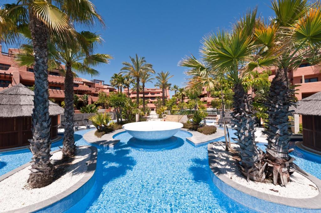 EsteponaMar Azul ApartHotel的一座种有棕榈树的大型游泳池以及一个喷泉