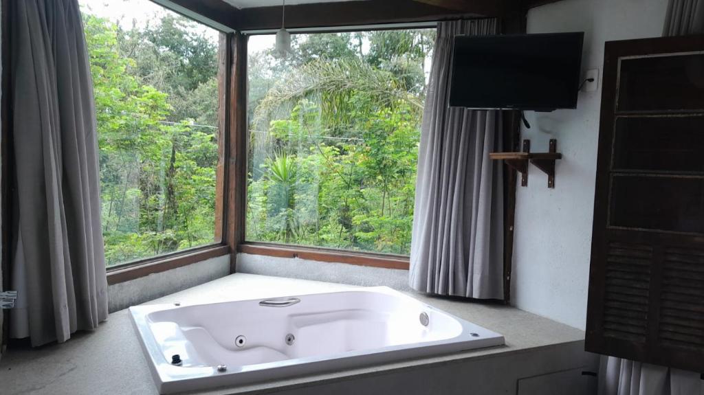 新利马Pousada Canto da Lua的带浴缸的浴室和大窗户