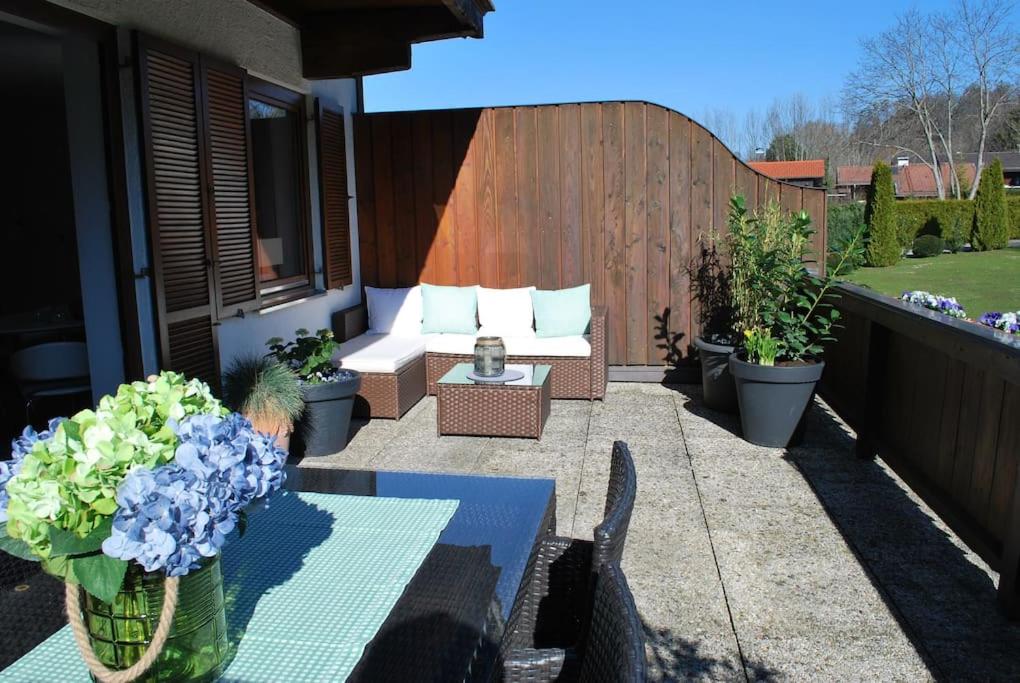 格门德蒂格斯Wohnung direkt am Tegernsee mit XL-Terrasse的天井配有沙发、桌子和鲜花