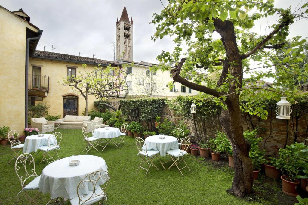 维罗纳伊尔瑞雷德尔阿巴匝酒店的一座带白色桌椅的花园以及一座建筑