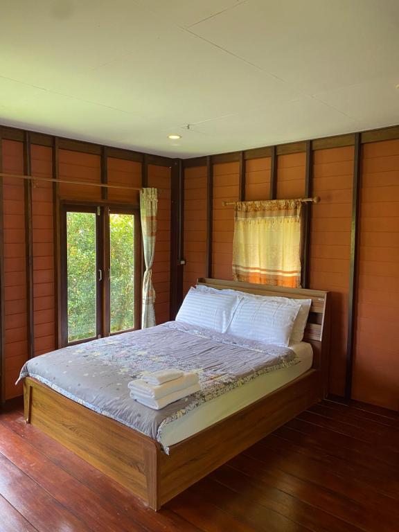 阁遥岛莫克达曼简易别墅度假屋的一间卧室配有一张带木墙和窗户的床。