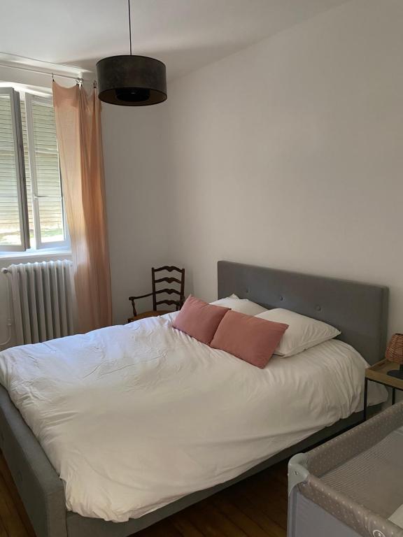 Maison chaleureuse avec piscine的卧室配有白色床和2个粉红色枕头