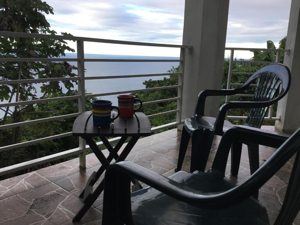 Tortola IslandAbigail's Spectacular 2 bedrooms-Entire Apartment的阳台配有2个杯子、桌子和椅子