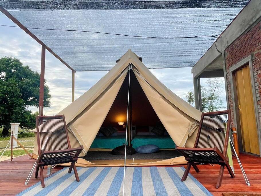 佩纳利克村Rembulan Escape - beachfront bell tent (no 1)的甲板上的帐篷,配有两把椅子