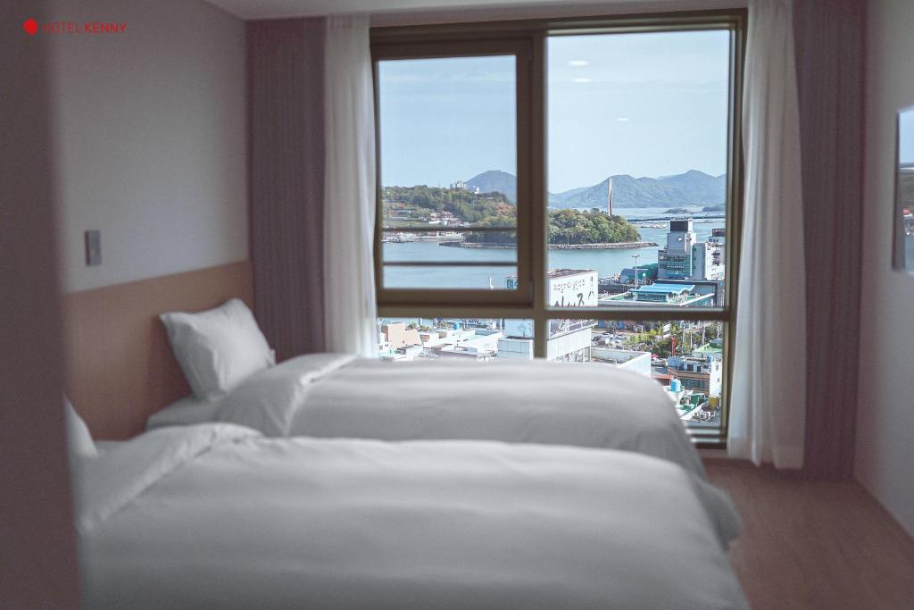 丽水市Hotel Kenny Yeosu的配有大窗户的酒店客房内的两张床